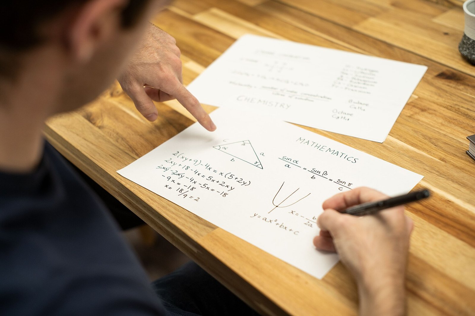Tutor pointing at a student's math worksheet